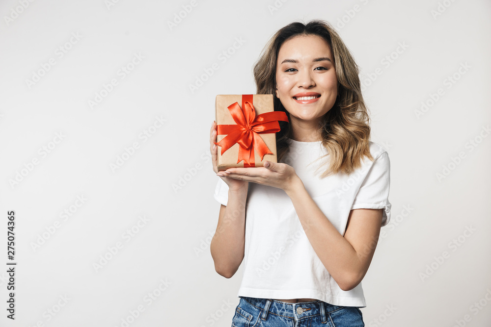 Emotional cute young woman posing isolated over white wall background holding present gift box. Emotional cute young woman posing isolated over white wall background holding present gift box.