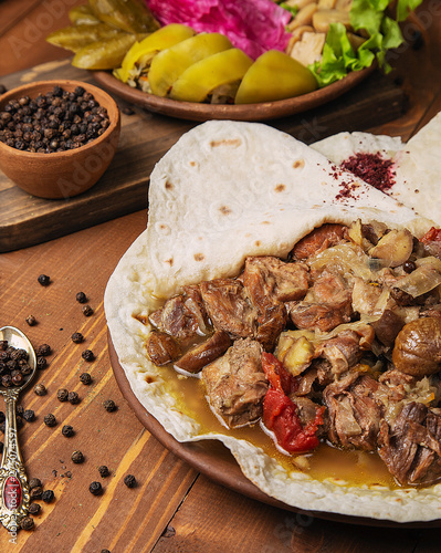 Meat stew, turshu govurma with onions, and chestnuts served in lavash. photo