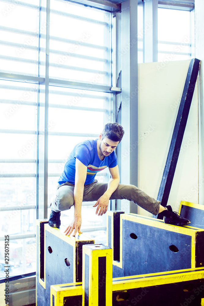 young handsome man doing parkour in gym inside, lifestyle sport people concept