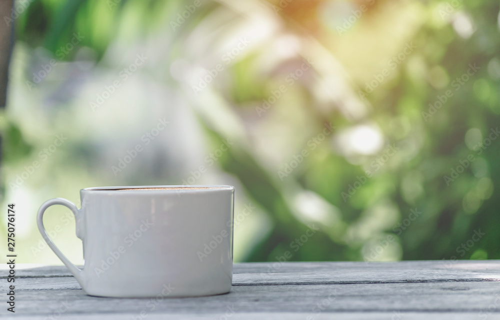 Hot coffee cup with white the wooden table and the Green leaf background with copy space on right Hot coffee cup with white the wooden table and the Green leaf background with copy space on right