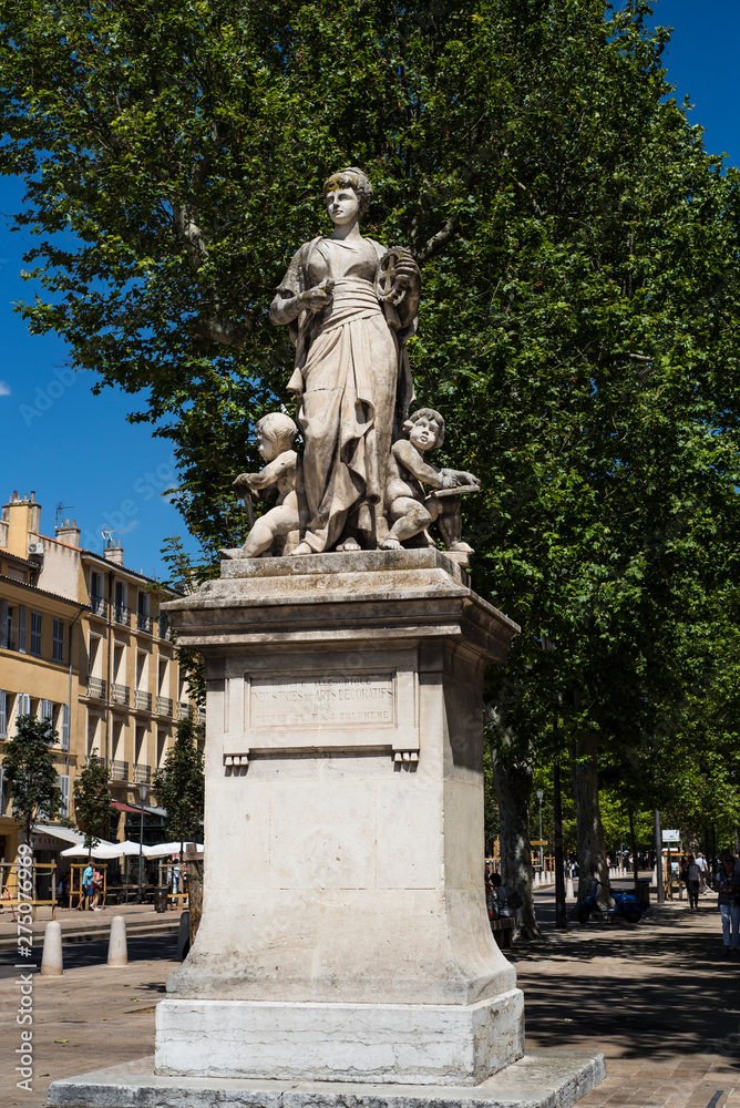 Stone feminin statue on the famous Aix-en-Provence street cours Mirabeau surrounded by green trees. France 2019.