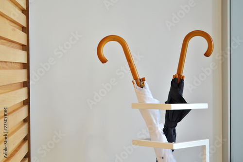 Black and white umbrella stand in special geometric stand against the white wall and wooden stand indoors