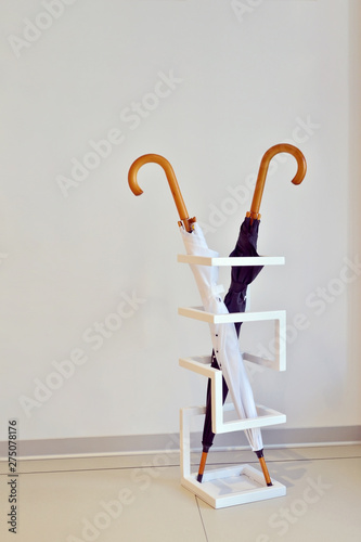 Black and white umbrella stand in a special geometric stand against white wall in the room