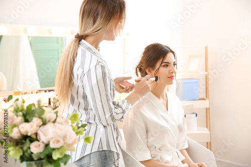 Professional makeup artist working with young bride at home