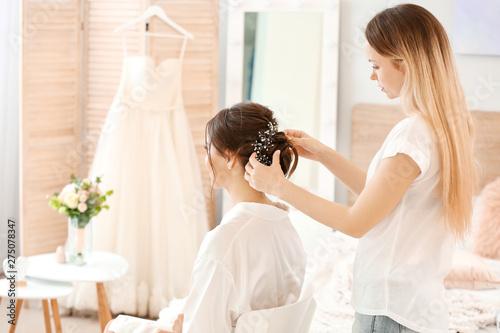 Professional hairdresser working with young bride at home