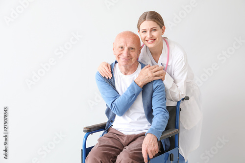 Elderly man with doctor on light background