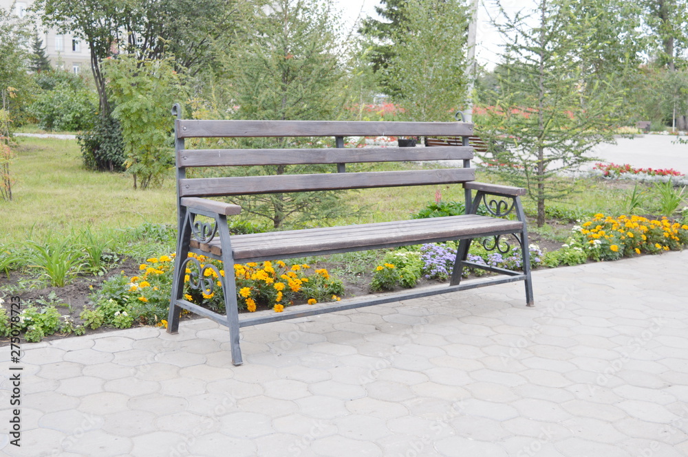 Wooden park bench among flowers and greenery Wooden park bench among flowers and greenery