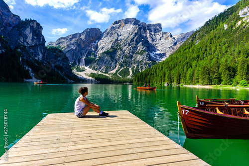 Woman relaxing on Pier at Lake Braies also known as Pragser Wildsee  in beautiful mountain scenery. Amazing Travel destination Lago di Braies in Dolomites, South Tyrol, Italy, Europe. © Simon Dannhauer