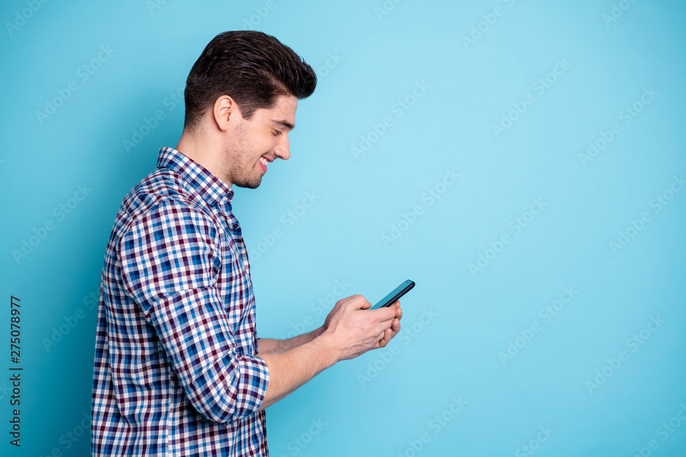 Side profile half turned photo portrait of confident positive optimistic excited involved interested carefree generation y guy holding digital telephone in hand leaving share post isolated background - obrazy, fototapety, plakaty 