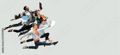 Happy office workers jumping and dancing in casual clothes or suit with folders isolated on studio background. Business, start-up, working open-space, motion and action concept. Creative collage. photo