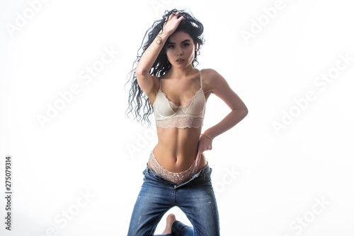 She got great style. sensual girl with curly hair. Flexible body. sexy woman in jeans and bra. fashion beauty. Diet and fitness.. erotic games. Isolated on white. woman with perfect body relax