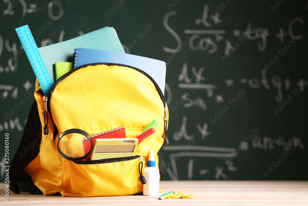 School backpack with stationery on table in classroom School backpack with stationery on table in classroom