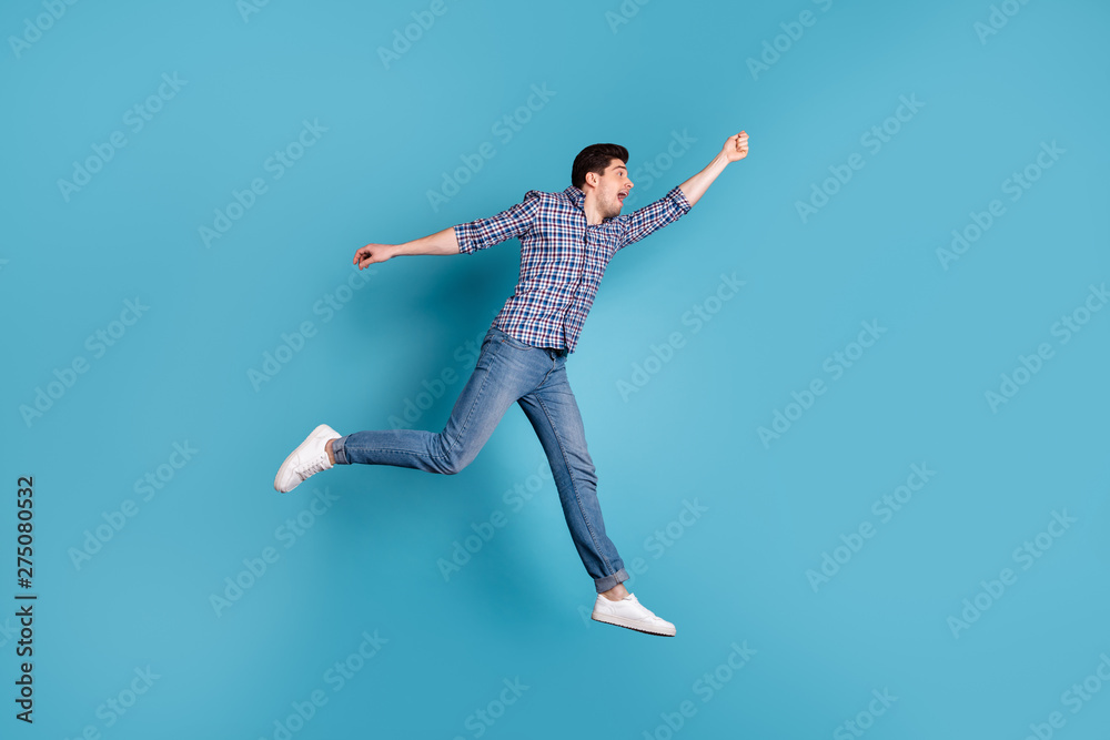Full length body size view photo of frightened millennial hold hand hang hanger scream shout wind blows dressed fashionable checkered clothing denim sneakers isolated on blue background