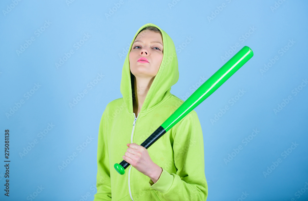 Girl hooded jacket hold baseball bat blue background. Woman in baseball sport. Baseball female player concept. She is dangerous. Girl troublemaker. Woman play baseball game or going to beat someone
