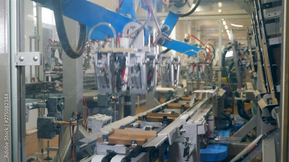 Robotic machine is making carton packages. Modern robotic factory equipment. Robotic machine is making carton packages. Modern robotic factory equipment.