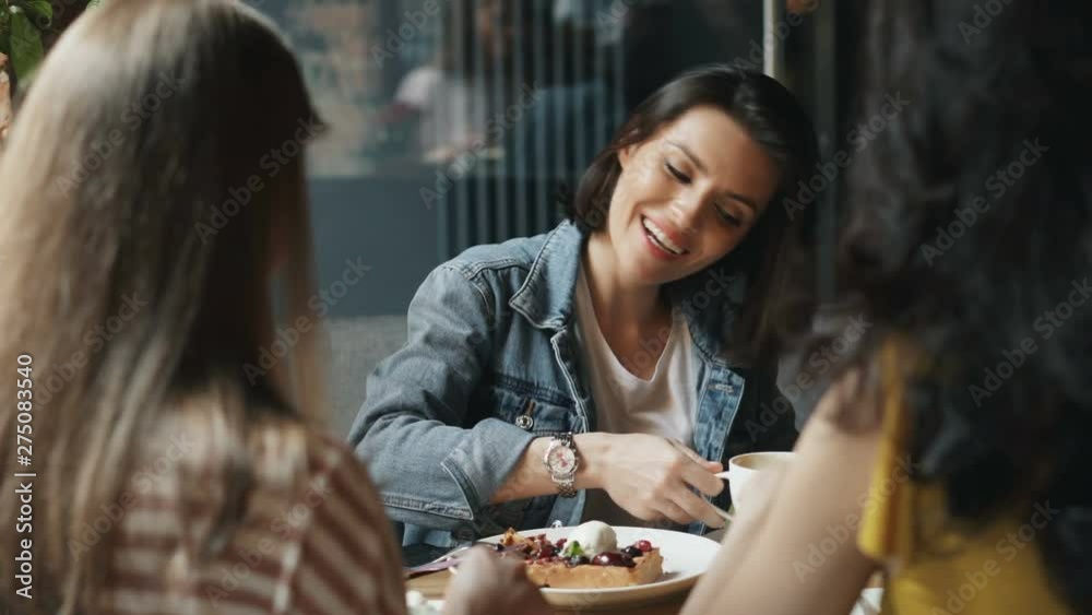 Young women are eating desserts and drinking coffee in cafe talking having fun enjoying leisure time and meeting with friends. People and happiness concept.