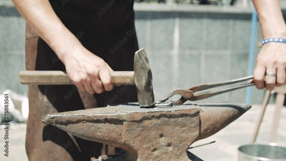 The blacksmith manually forged a heart out of metal. With a hammer and tongs, he corrects the shape of a metal heart.