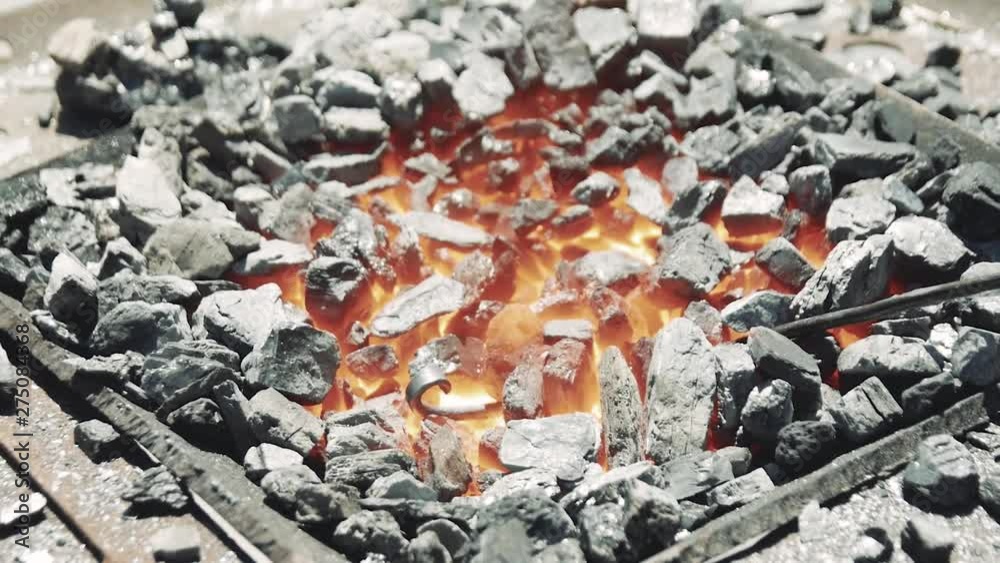 Close Up of Hot Metal Bar Being Heated in a Coal Forge in the Blacksmith Shop with Flame. Metal parts are being heated in the furnace and prepared for forging in blacksmith workshop. Close Up of Hot Metal Bar Being Heated in a Coal Forge in the Blacksmith Shop with Flame. Metal parts are being heated in the furnace and prepared for forging in blacksmith workshop.