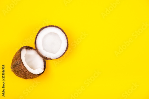 Top view of halved ripe coconut on bright yellow background. Copy space.