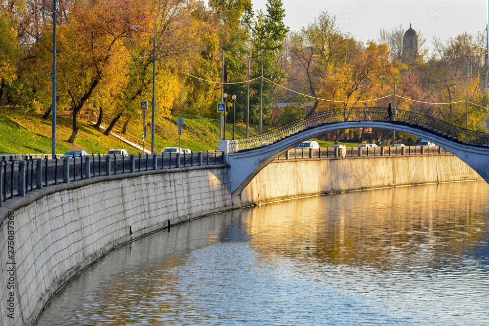 Autumn. View of the bridge over the river in the city where there is a person