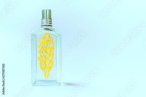 Transparent perfume bottle on a blue background decorated with yellow flower petals