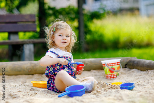 Foto Cute toddler girl playing in sand on outdoor playground