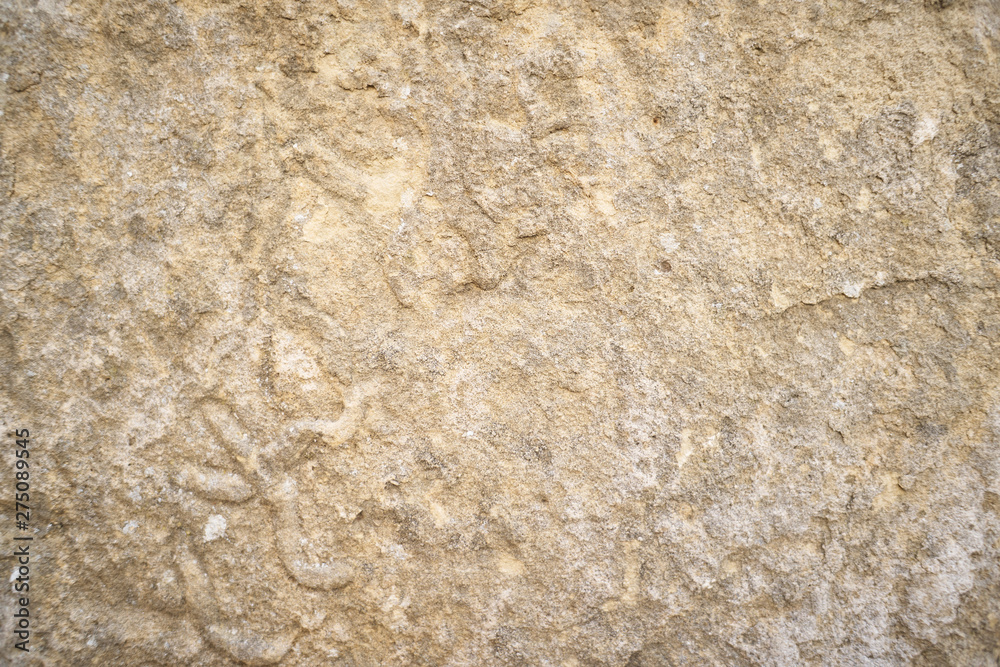 Stone surface. Beautiful background texture sandstone stone. The surface of the stone has a pleasant warm shade of light orange yellow-brown color with many large and small irregularities.