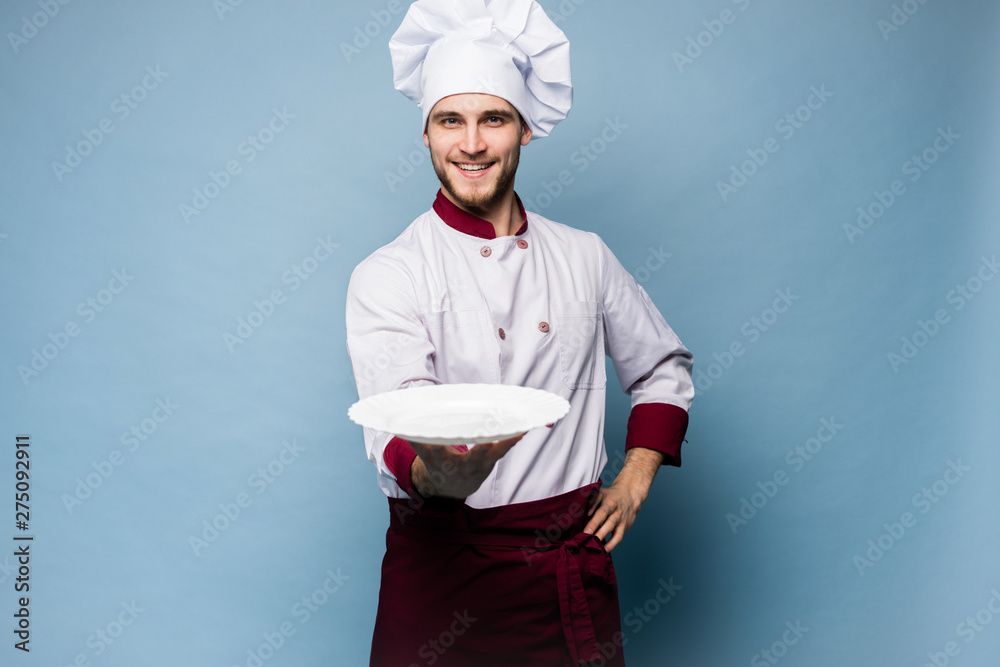 Portrait of a happy male chef cook standing with plate isolated on light blue background. Portrait of a happy male chef cook standing with plate isolated on light blue background.