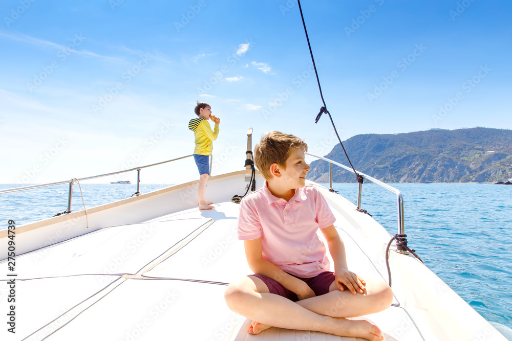Two little kid boys, best friends enjoying sailing boat trip. Family vacations on ocean or sea on sunny day. Children smiling. Brothers, schoolchilden, siblings, best friends having fun on yacht. Two little kid boys, best friends enjoying sailing boat trip. Family vacations on ocean or sea on sunny day. Children smiling. Brothers, schoolchilden, siblings, best friends having fun on yacht.
