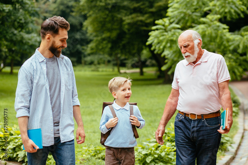 Three different generations together Affectionate dad and granddad seeing their little boy off to elementary school. Mans support, love, parentship, care concept. Back to school. First day of fall. © Iryna