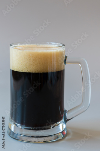 Glass of dark beer on a gray background. vertical photo