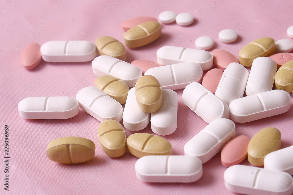 Different pills on pink background