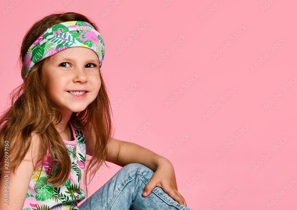 Little cute blonde girl preschooler in summer t-shirt and bandana bandage smiling at camera over pink background