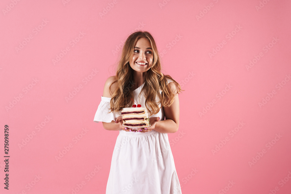 Image of happy confused woman wearing white dress looking aside and holding piece of cake Image of happy confused woman wearing white dress looking aside and holding piece of cake