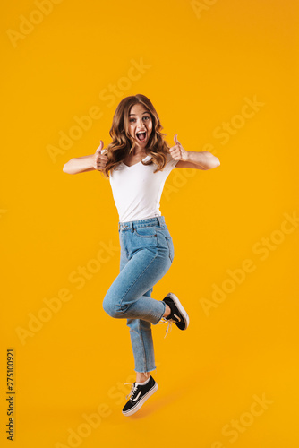 Full length image of astonished attractive caucasian woman wearing basic t-shirt rejoicing and showing thumbs up