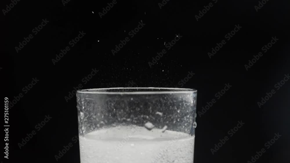 Effervescent aspirin tablet dropping to glass of water. Slow motion fizzy pill falls and dissolves with bubbles. Medicine, health care pharmacy chemistry concept