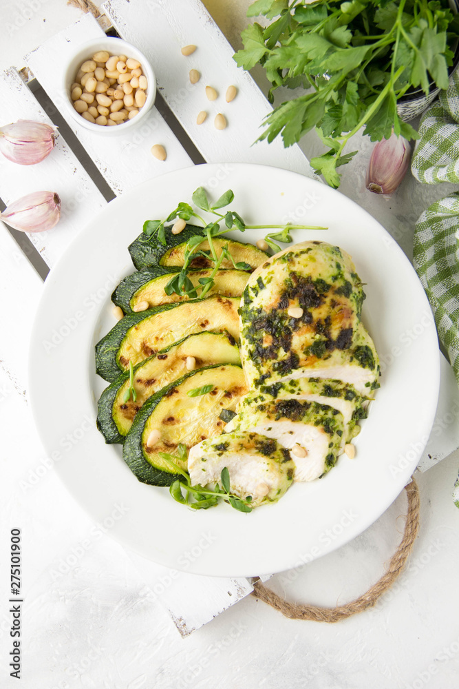 Grilled chicken fillet with green herb marinade, with slices of fried zucchini and pine nuts, healthy lunch