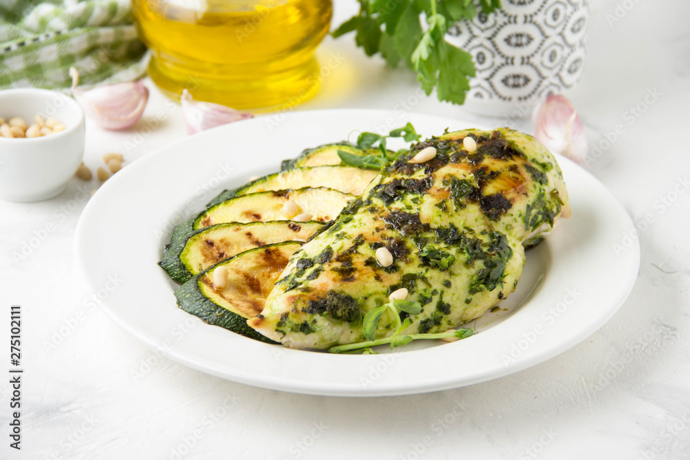 Grilled chicken fillet with green herb marinade, with slices of fried zucchini and pine nuts, healthy lunch