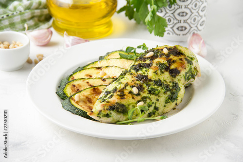 Grilled chicken fillet with green herb marinade, with slices of fried zucchini and pine nuts, healthy lunch