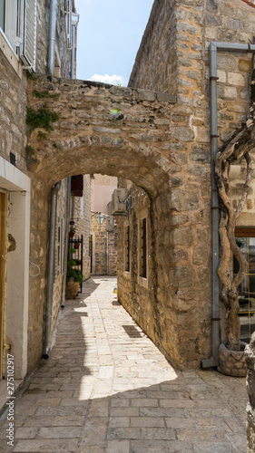Fototapeta Naklejka Na Ścianę i Meble -  Picturesque narrow street in old town of Budva, Montenegro. Ancient houses. Stone arch inside the fortress