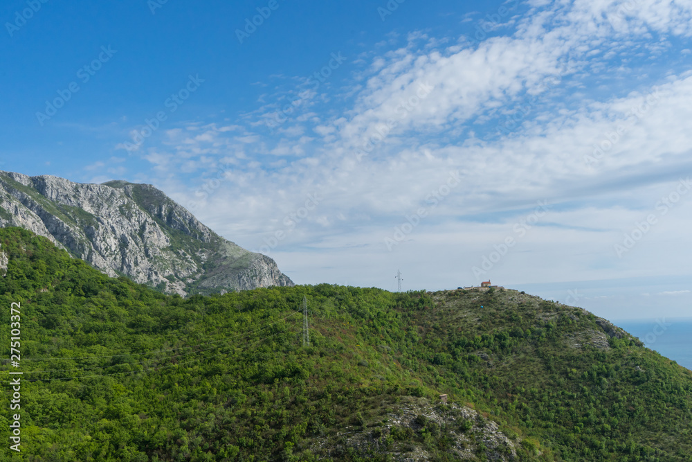 Obraz premium Mountains in the Balkans mountains. Green cliff with forest and clouds in the sky. Adriatic sea in Montenegro. Tropical view