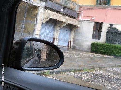 car side mirror and side window on a rainy day across city streets. Sad mood concept. 