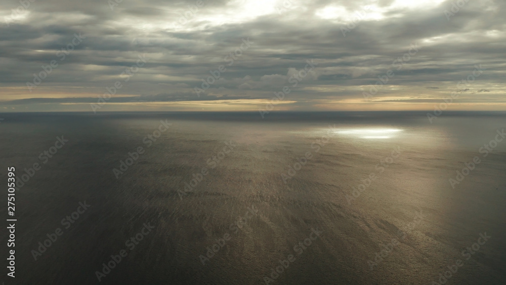 Dramatic sky with clouds over the sea during sunset in cloudy weather, aerial view. Sunset over ocean. Seascape, Summer and travel vacation concept