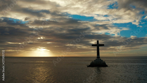 Catholic cross in sunken cemetery in the sea at sunset, aerial drone. Large crucafix marking the underwater sunken cemetary, Camiguin Island Philippines. photo