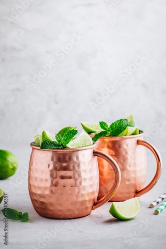 Cuadro en lienzo Moscow mule ice cold cocktail in copper cup with lime and and mint on gray stone