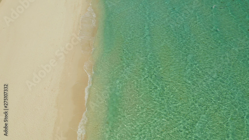Sea water surface in lagoon with sandy beach and wave, copy space for text, aerial view. Top view transparent turquoise ocean water surface. background texture