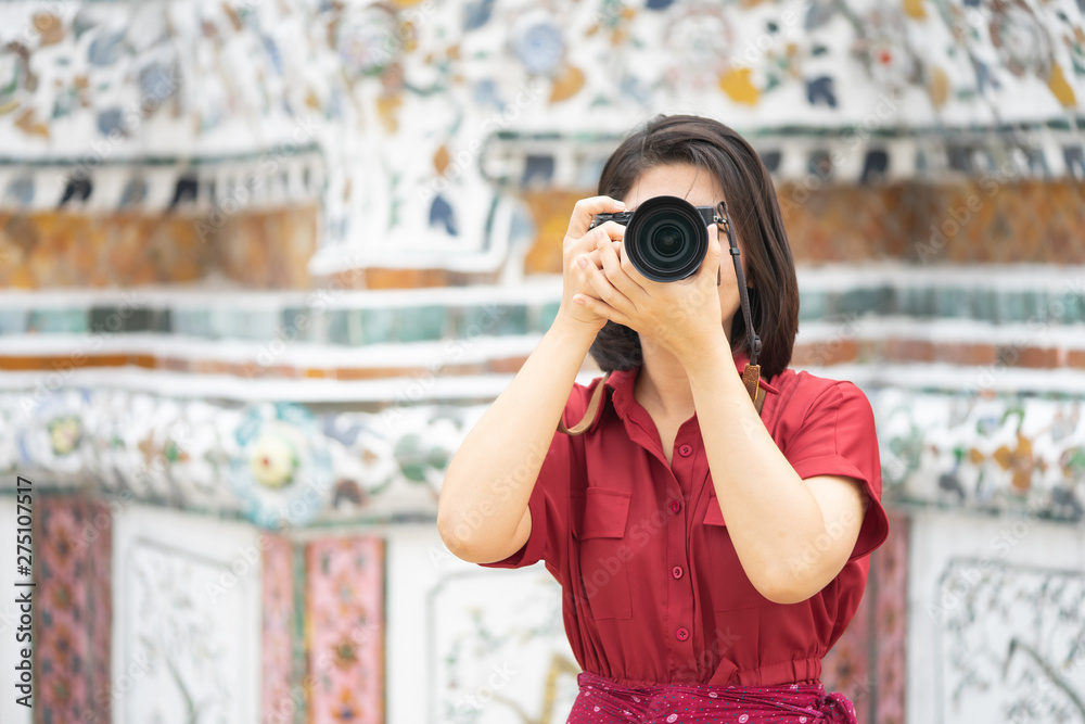 Beautiful woman tourist Held camera to capture the memories. Wat Arun Temple in Thailand. using as background  travel concept with copy spaces for your