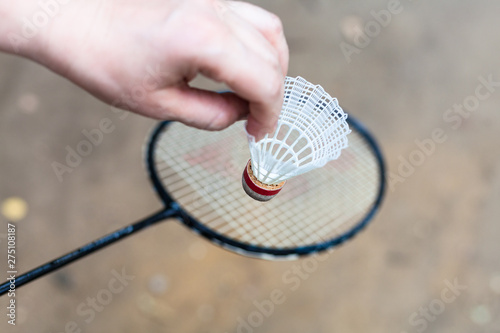 hand holds shuttlecock over badminton racquet
