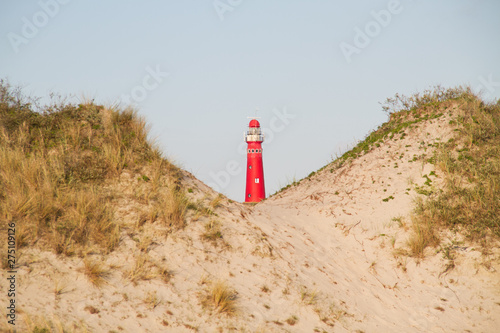 View between two dunes on the red lighthouse of the Dutch island Schiermonnikoog