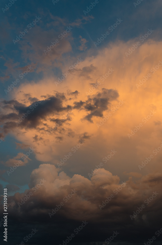 Dramatic clouds of thunderstorm in orange sunlight. Sunset on summer evening.